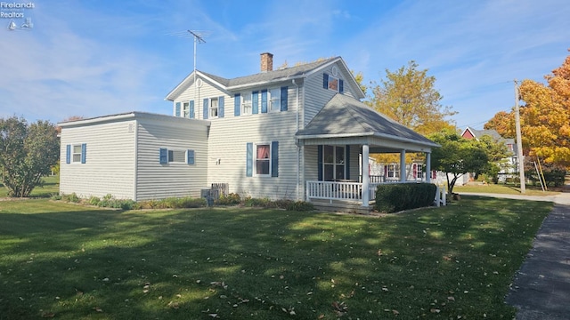 rear view of house featuring a lawn and a porch