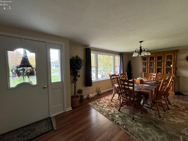 dining room with dark wood-type flooring, a notable chandelier, and a textured ceiling