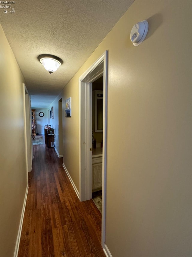 hallway with a textured ceiling and dark wood-type flooring