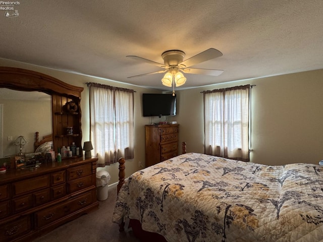 carpeted bedroom with a textured ceiling, multiple windows, and ceiling fan