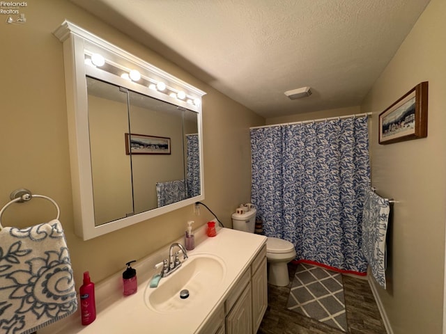 bathroom featuring toilet, a textured ceiling, hardwood / wood-style flooring, and vanity