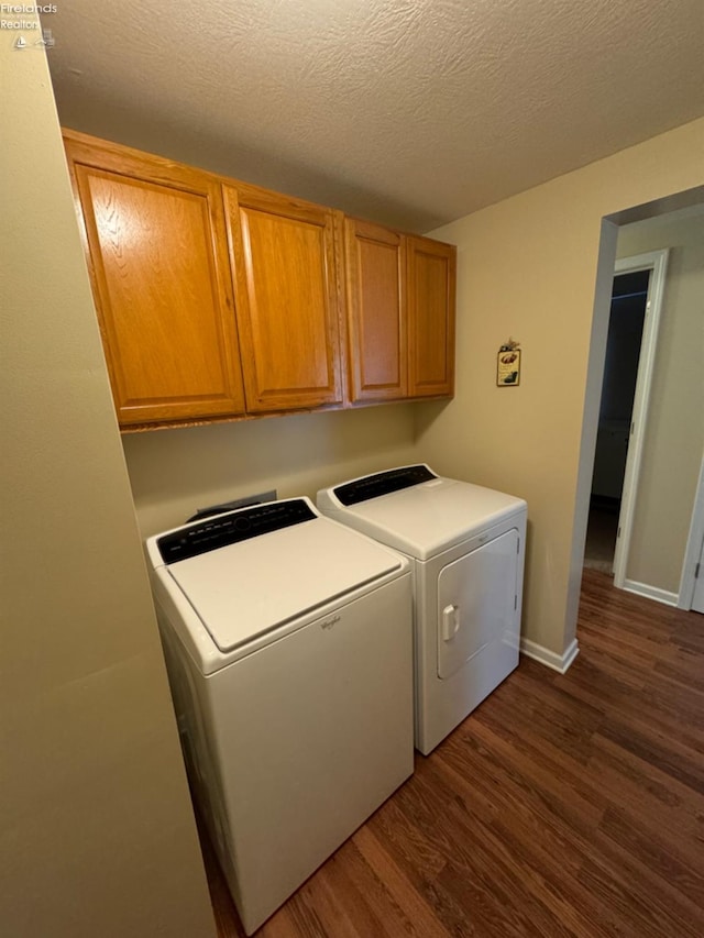 laundry area featuring cabinets, independent washer and dryer, dark hardwood / wood-style floors, and a textured ceiling