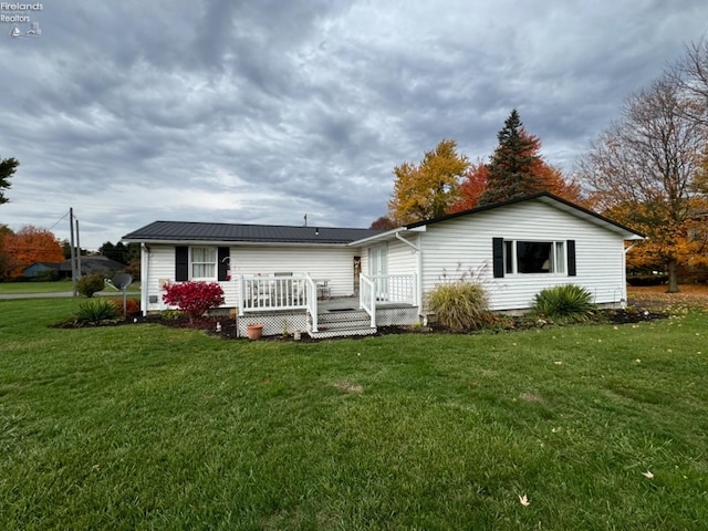 rear view of property with a wooden deck and a yard