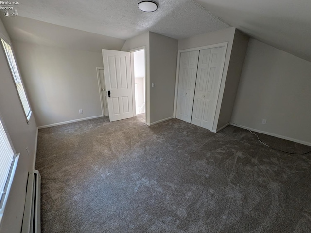 bonus room with baseboard heating, lofted ceiling, dark colored carpet, and a textured ceiling