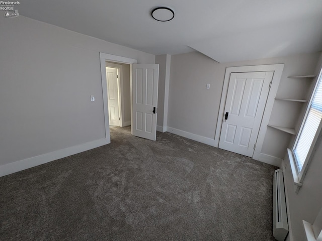 interior space with a closet, a baseboard heating unit, and dark colored carpet