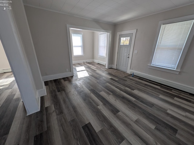 foyer featuring baseboard heating, dark wood-type flooring, and crown molding