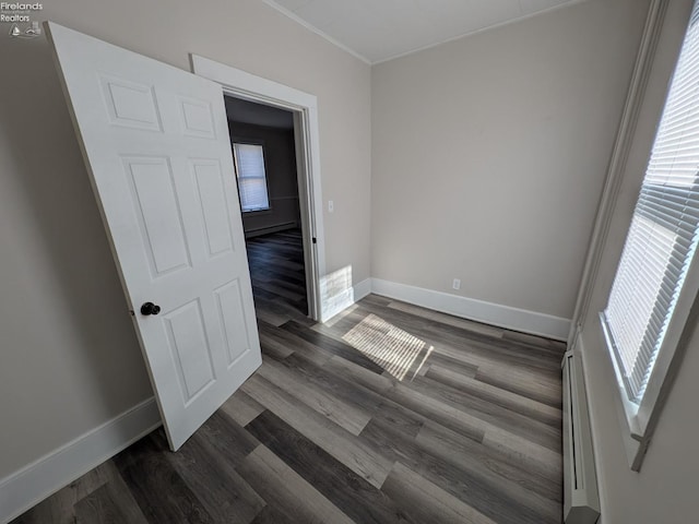 unfurnished room featuring baseboard heating and dark wood-type flooring