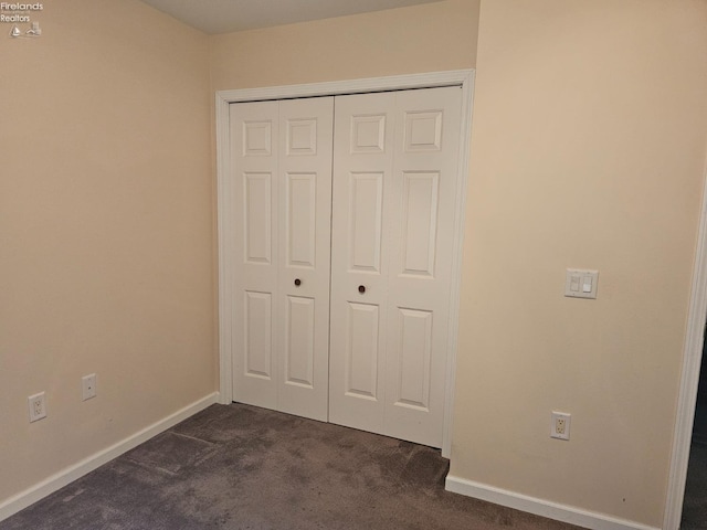 unfurnished bedroom with a closet and dark carpet