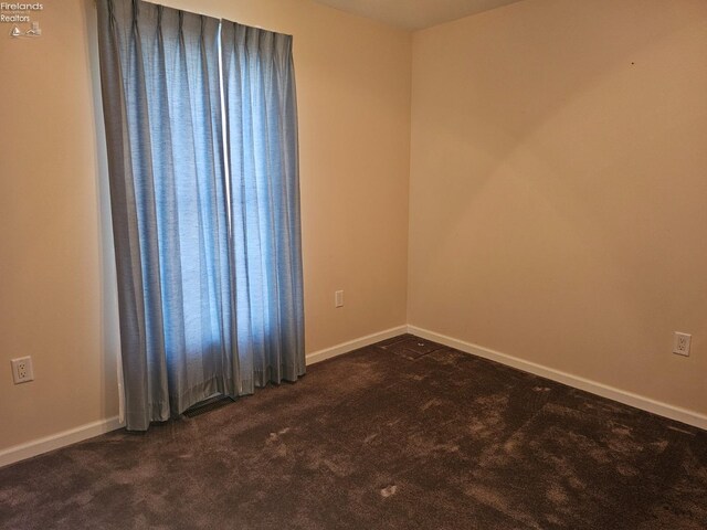 unfurnished room featuring dark carpet