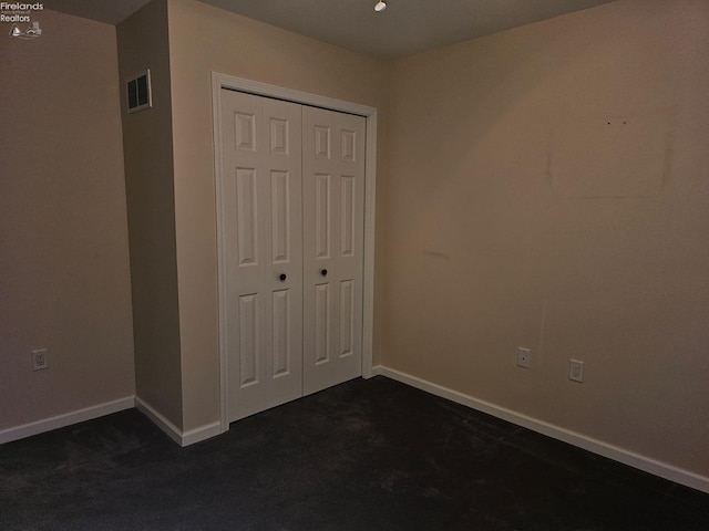 unfurnished bedroom with a closet and dark carpet