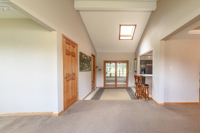 entryway featuring beam ceiling, high vaulted ceiling, carpet flooring, and a skylight