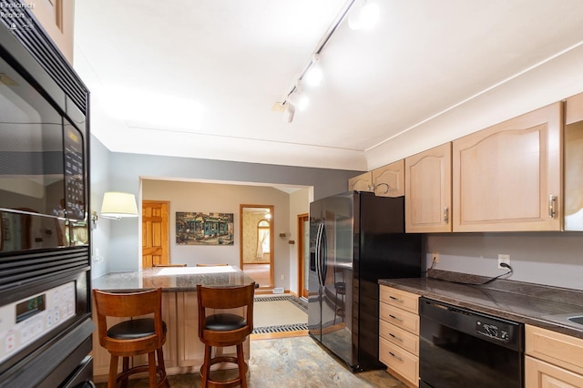 kitchen featuring rail lighting, light brown cabinetry, black appliances, and a breakfast bar