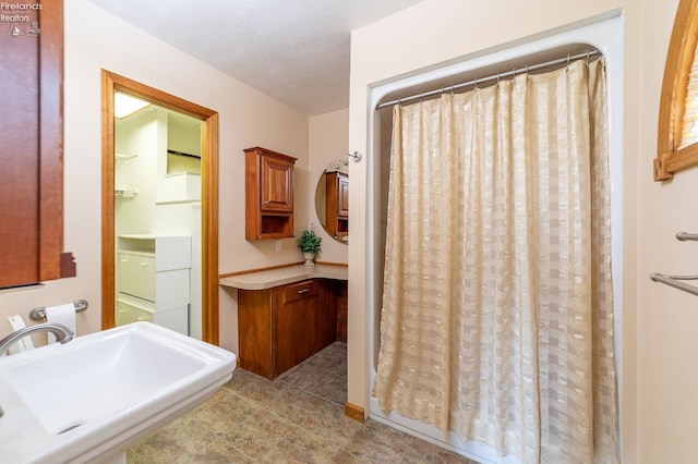 bathroom with a textured ceiling, a shower with curtain, sink, and tile patterned floors