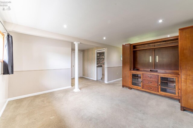 unfurnished living room featuring light colored carpet and decorative columns