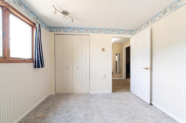 unfurnished bedroom with a closet and light colored carpet