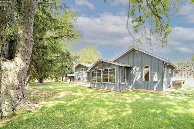 back of house with central air condition unit and a lawn