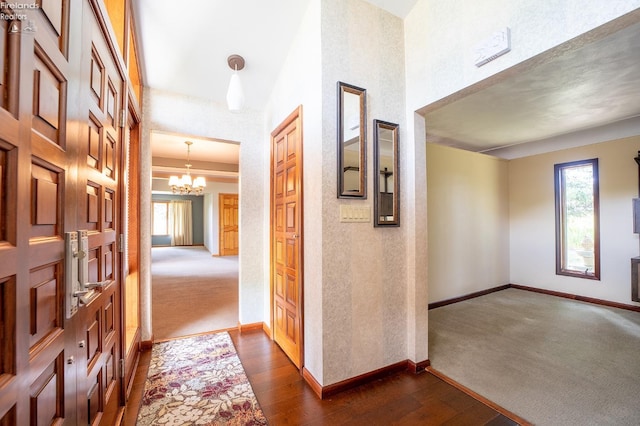 corridor featuring dark wood-type flooring and an inviting chandelier