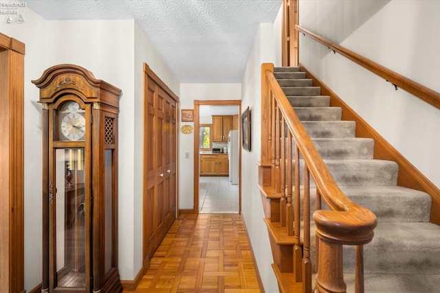 staircase featuring parquet floors and a textured ceiling