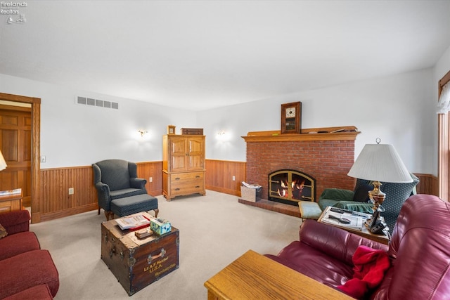 living room with light carpet, a brick fireplace, and wood walls