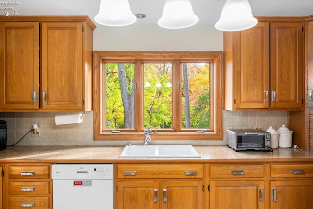 kitchen with backsplash, white dishwasher, sink, and hanging light fixtures