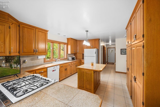 kitchen featuring white appliances, tasteful backsplash, sink, a center island, and pendant lighting