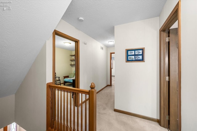 corridor with light carpet and a textured ceiling