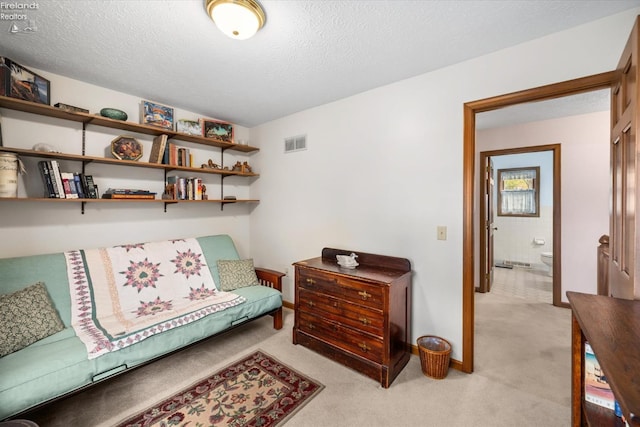 living area with a textured ceiling and light colored carpet