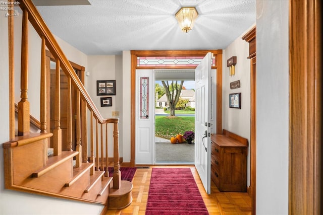 foyer entrance with parquet flooring and a textured ceiling