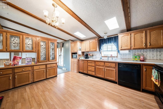 kitchen with black appliances, lofted ceiling with skylight, a textured ceiling, hanging light fixtures, and light hardwood / wood-style flooring