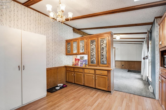 kitchen featuring hanging light fixtures, a textured ceiling, light wood-type flooring, and vaulted ceiling with beams