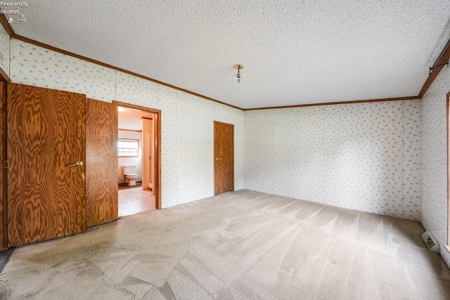 unfurnished room featuring ornamental molding, carpet flooring, and a textured ceiling