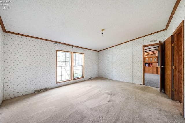 carpeted empty room featuring a textured ceiling and ornamental molding