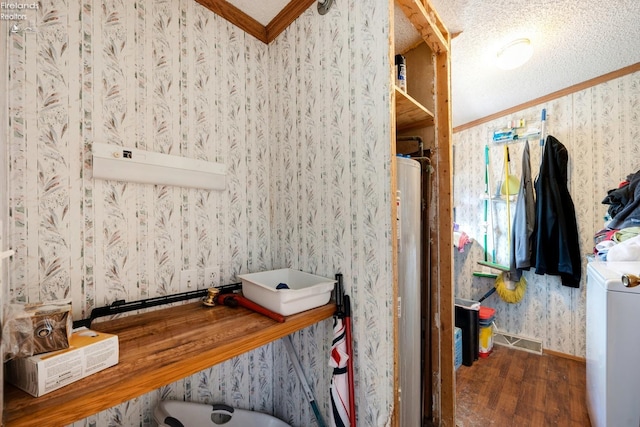 bathroom featuring ornamental molding, a textured ceiling, hardwood / wood-style floors, washer / dryer, and water heater