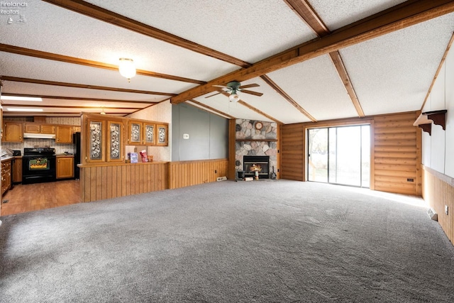 unfurnished living room with a stone fireplace, a textured ceiling, carpet, ceiling fan, and lofted ceiling with beams