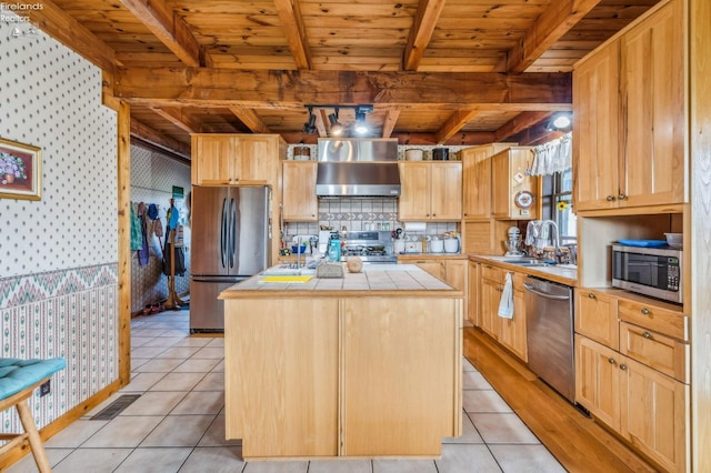 kitchen with wall chimney range hood, tile countertops, stainless steel appliances, sink, and a center island