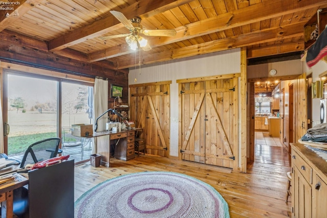 office space featuring beam ceiling, a barn door, light wood-type flooring, and ceiling fan