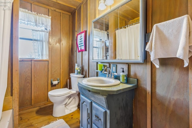 full bathroom with plus walk in shower, hardwood / wood-style flooring, toilet, vanity, and wood walls