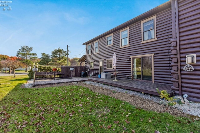 rear view of house with central air condition unit, a deck, and a lawn