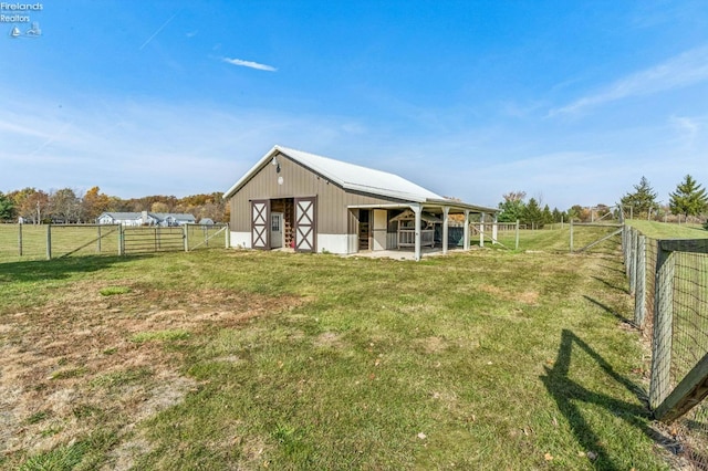 rear view of property featuring a rural view and an outbuilding