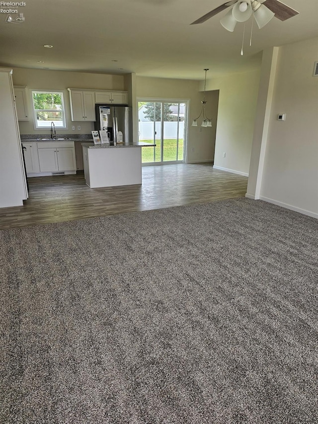 unfurnished living room with dark wood-type flooring, ceiling fan, and sink