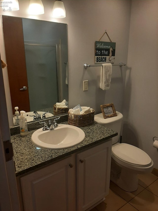 bathroom with vanity, a shower with shower door, toilet, and tile patterned floors