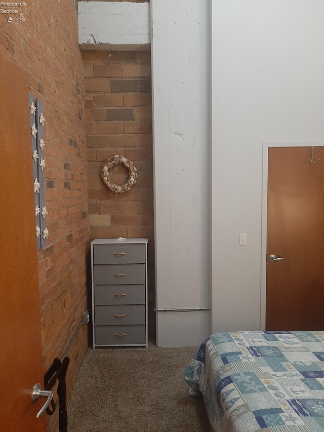 carpeted bedroom featuring brick wall