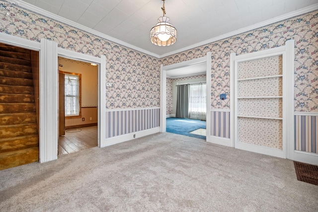 unfurnished room featuring ornamental molding, carpet flooring, built in features, and plenty of natural light