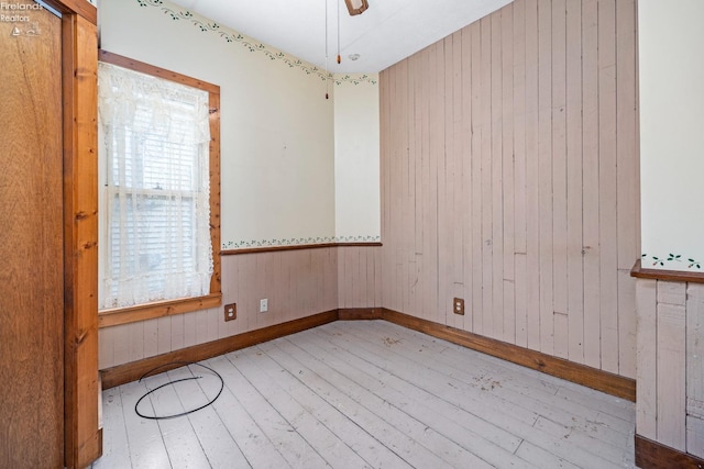 empty room with wood walls and light wood-type flooring