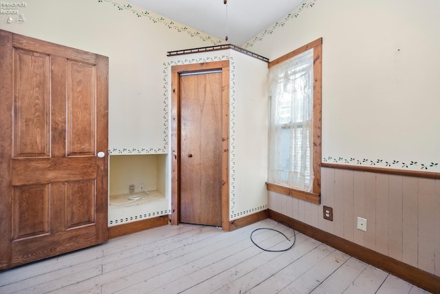 unfurnished bedroom with wooden walls and light wood-type flooring