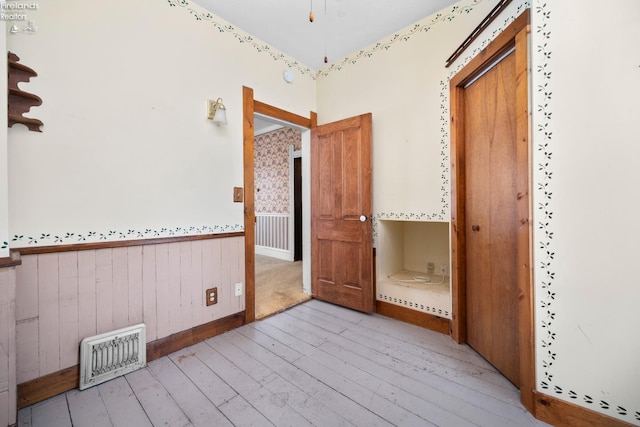 unfurnished bedroom featuring wooden walls and light wood-type flooring