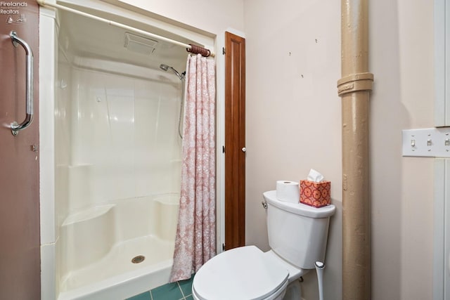 bathroom featuring a shower with curtain, toilet, and tile patterned flooring