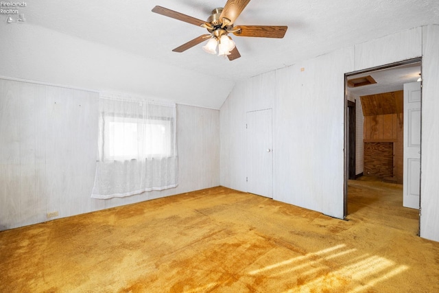 carpeted empty room with ceiling fan, a textured ceiling, and vaulted ceiling