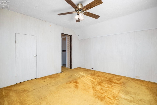 unfurnished bedroom featuring ceiling fan, a textured ceiling, vaulted ceiling, and carpet floors