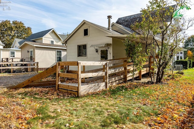 back of property featuring a wooden deck and a yard